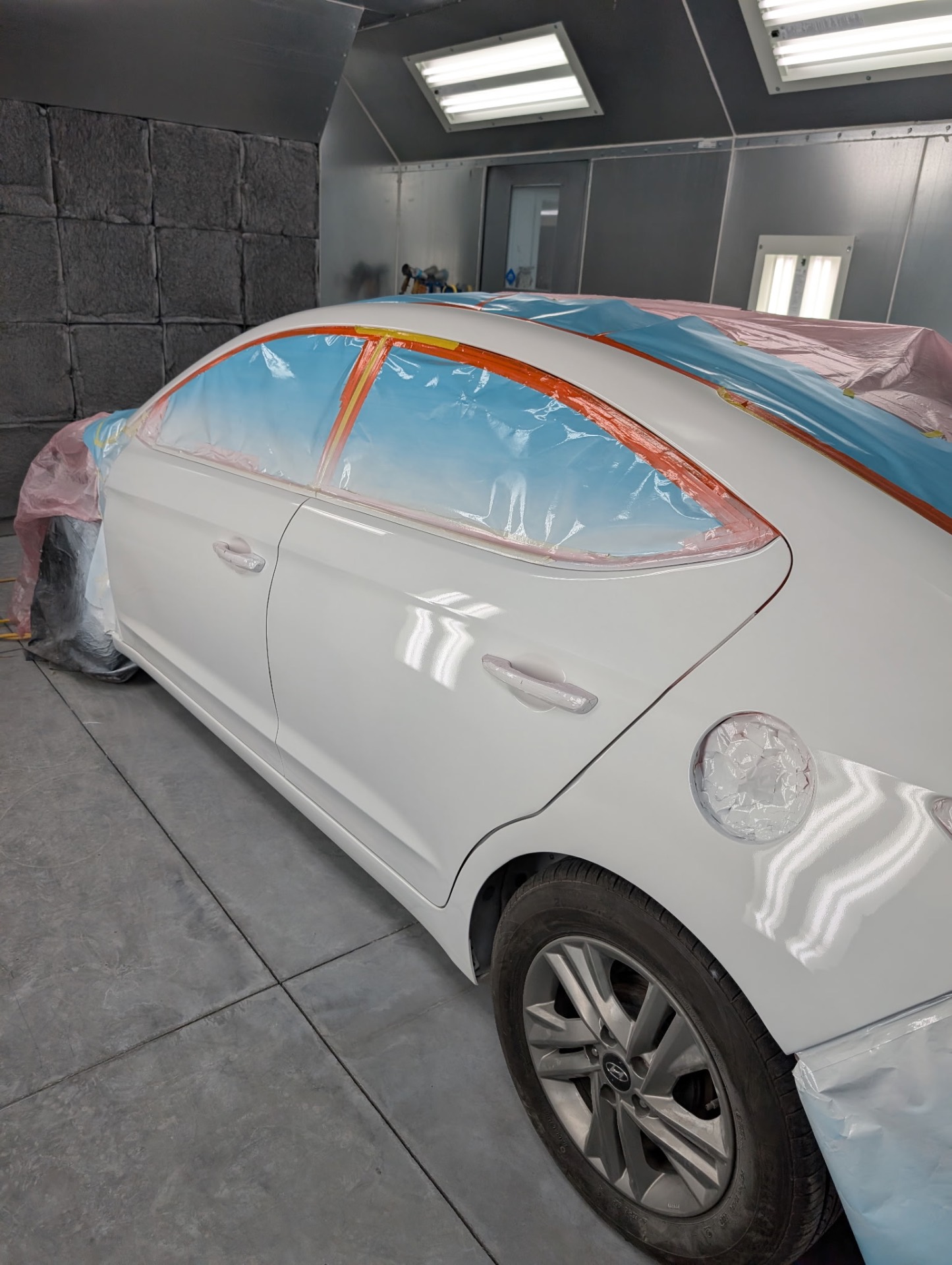 Freshly refinished sedan gleaming under the shop lights at Broz Auto Body